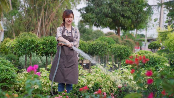 年轻的女花匠在花店浇花