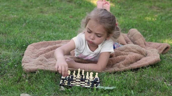 焦虑的小女孩在公园的棋盘上摆好棋子