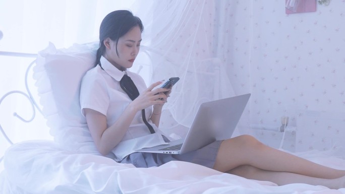一名东方女性在卧室床上坐着玩手机
