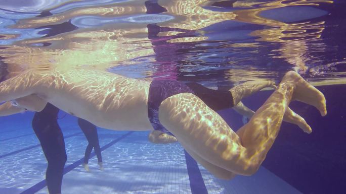 周末休闲时间在游泳池练习呼吸运动的亚洲水下老年人在教练的监督下