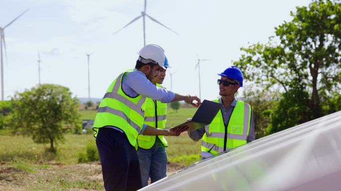 蓝领工人电气工程师团队和建筑师持有风车场和太阳能电池板施工的咨询计划。景观设计使用风力涡轮机来产生纯