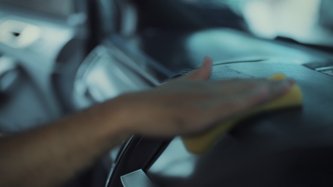 汽车详细清洁服务在汽车详细清洁服务期间，一名年轻男子在清洁座椅软垫时使用细布对内部进行深度清洁。