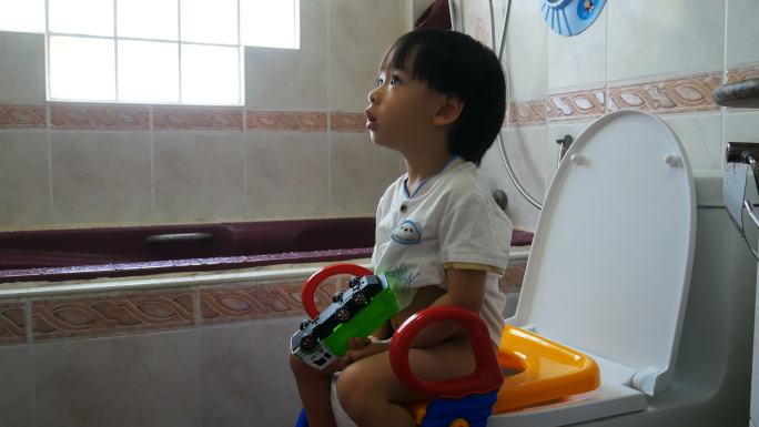 亚洲小男孩坐在浴室的马桶上