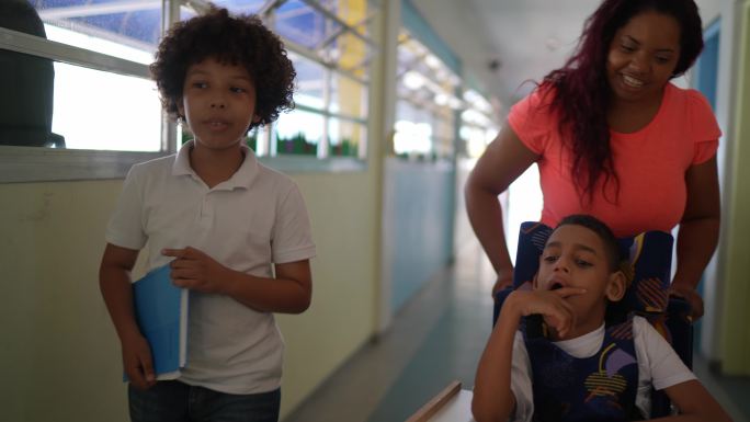 老师和学生在学校走廊里行走——包括一个残疾男孩