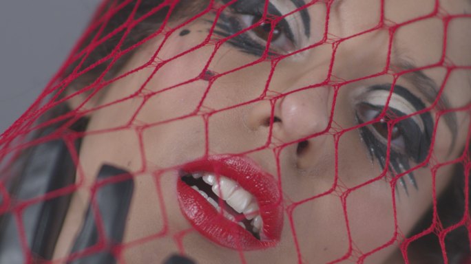 被困在红网中的性感黑发时装模特展示面部表情。时尚视频。