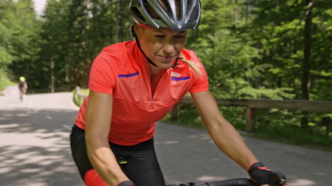 一名女子骑着公路自行车上了一条被森林环绕的山路