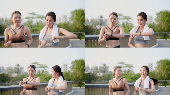 正面图：两位亚洲美丽的中年女性朋友穿着运动装，拥有完美的肌肉，一起积极慢跑，使用智能手表监控，在人行