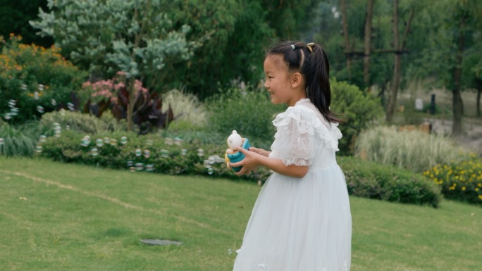 小女孩在草坪上玩泡泡