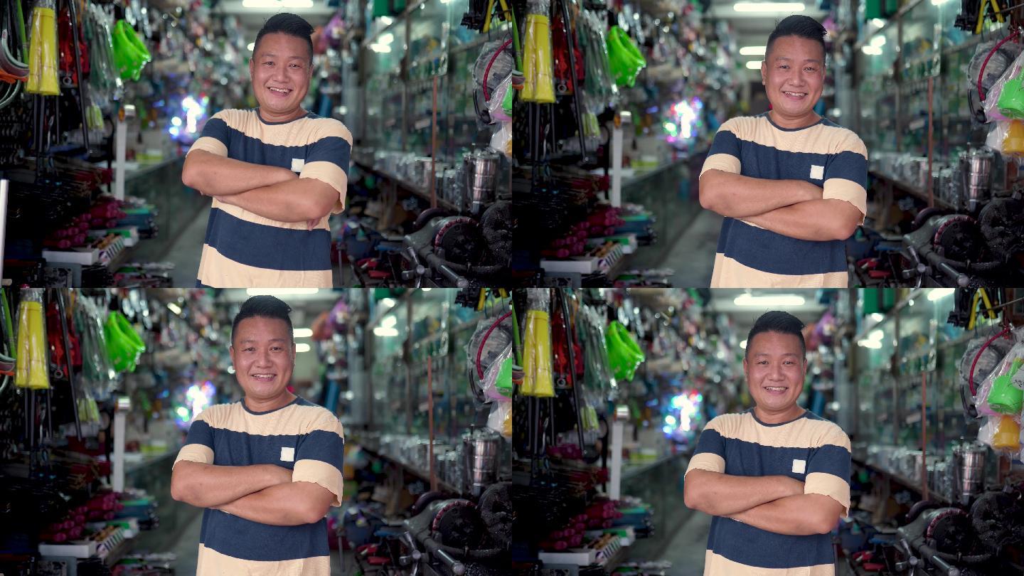 一位亚裔华人老板微笑着看着五金店前的摄像机。像