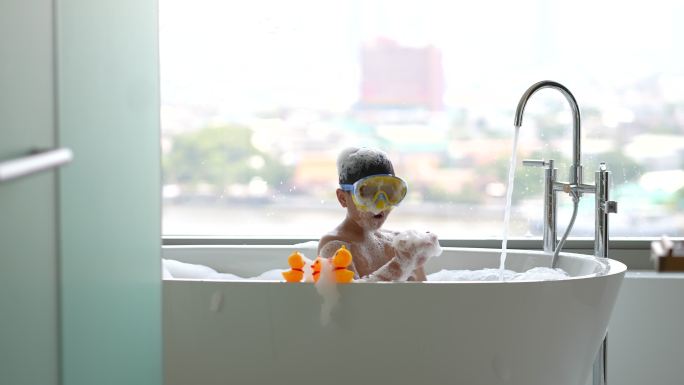 亚洲孩子在酒店的浴缸里玩着通气面罩和黄鸭子。健康与幸福的概念