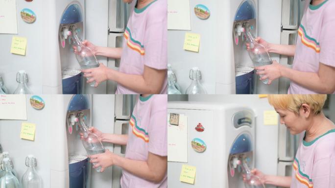 女人在家里用玻璃瓶装水净水器