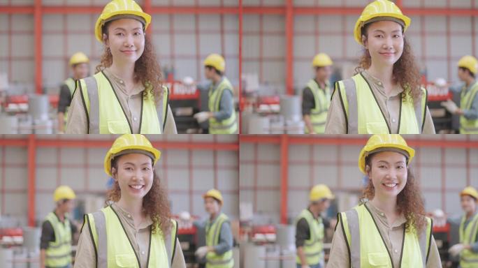 专业工业女性工程师或技师的肖像，有自信和领导力，穿戴个人防护装备，站在制造工厂，微笑着看着相机。