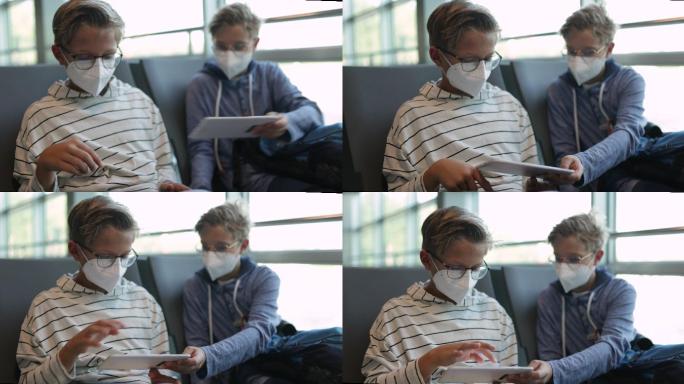 十几岁的男孩在机场等待并玩智能设备
