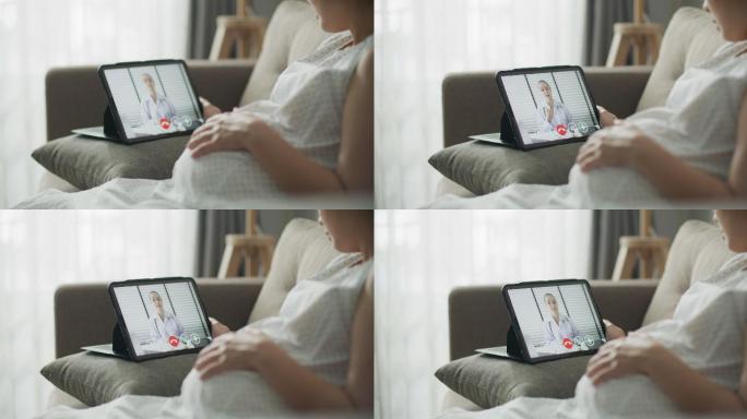 亚洲孕妇在家通过数字平板电脑与医生进行视频通话