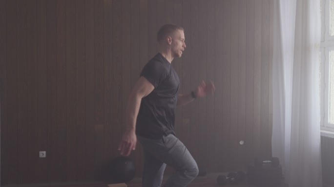 有氧运动：英俊的运动员在室内健身房做高膝运动（复制空间）