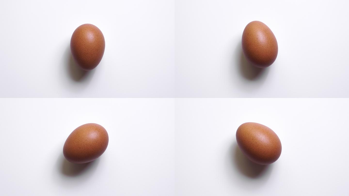 4k停止运动：白色背景下旋转鸡蛋的俯视图