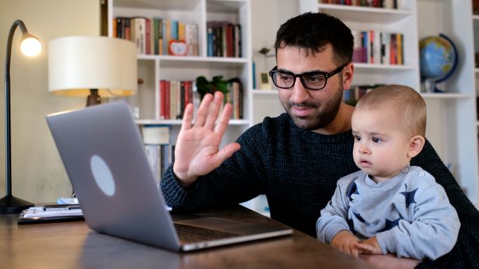 一个年轻人带着他的儿子在笔记本电脑上进行视频通话