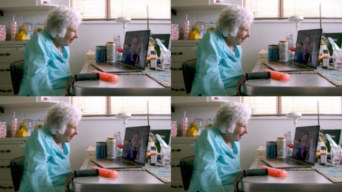 一位100岁的老妇人坐在笔记本电脑前与孙子交谈并打视频电话