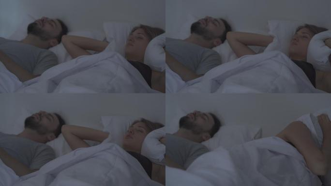 丈夫打鼾，妻子用枕头捂着头。