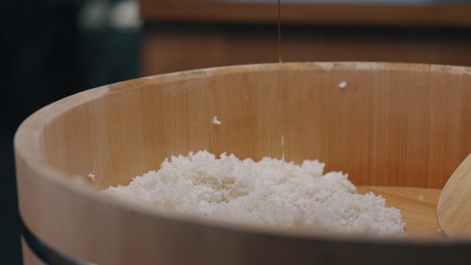 日本寿司厨师将米林倒在Hangiri木碗里的寿司米饭上