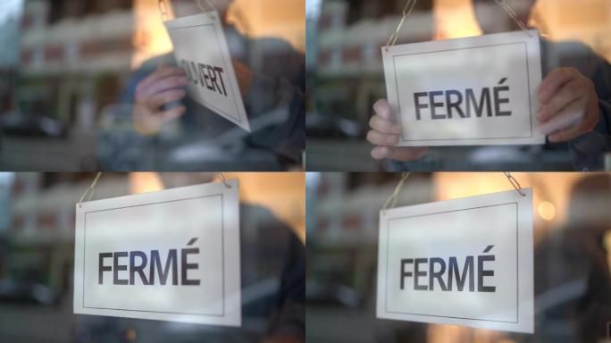 店主转向店面门上的关闭标志（fermé）