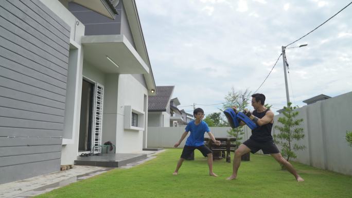 中国亚裔青少年和父亲在后院练习跆拳道