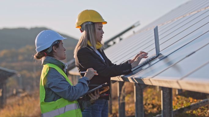 在太阳能发电厂工作的女性工程师。团队合作可再生能源系统。太阳能城。