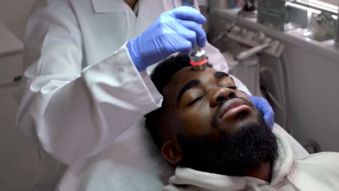 美容师在对放松的男性顾客进行面部治疗时的特写镜头