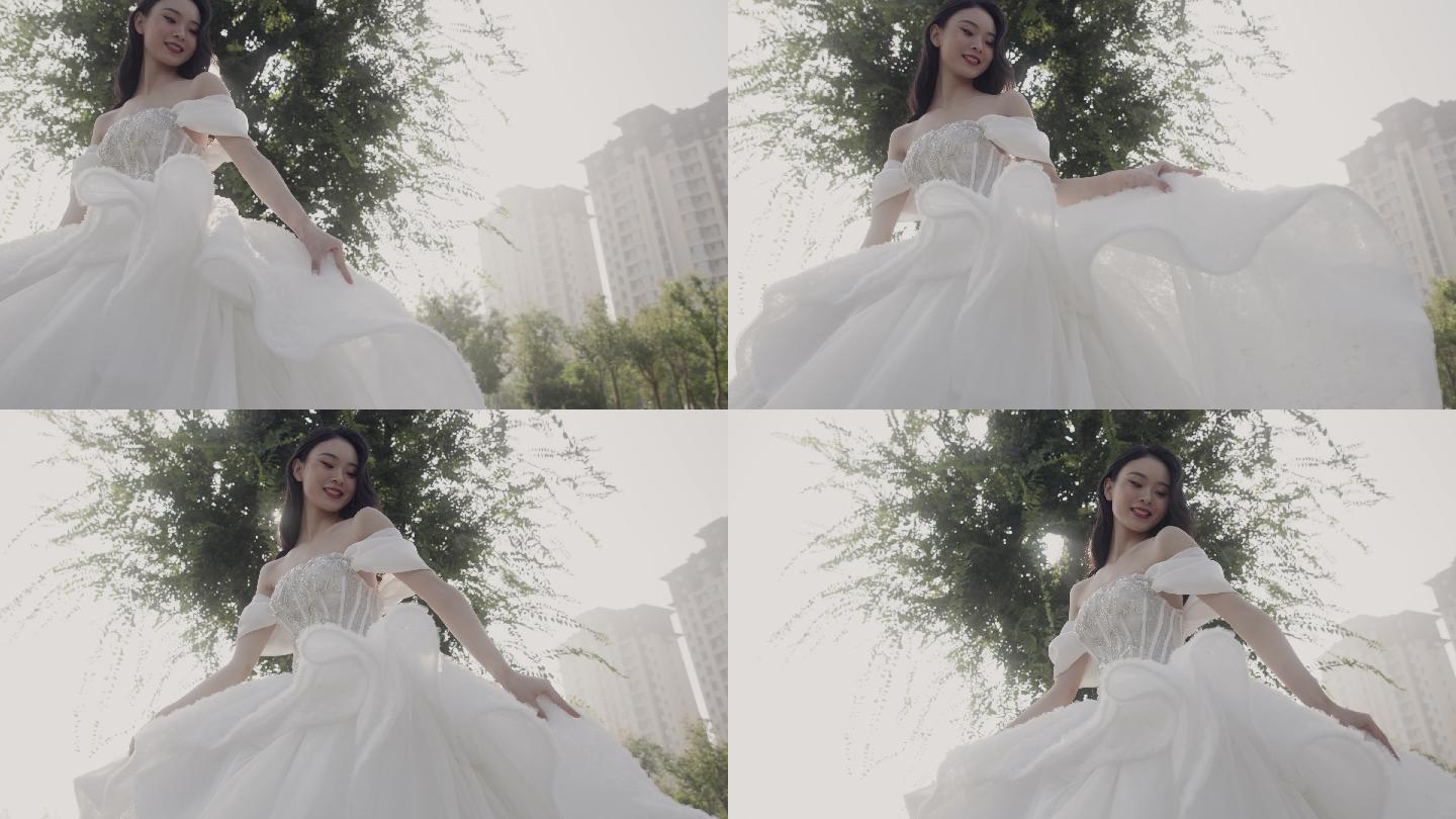穿着白色长尾婚纱的年轻亚洲女孩对着镜头微笑，新娘快乐