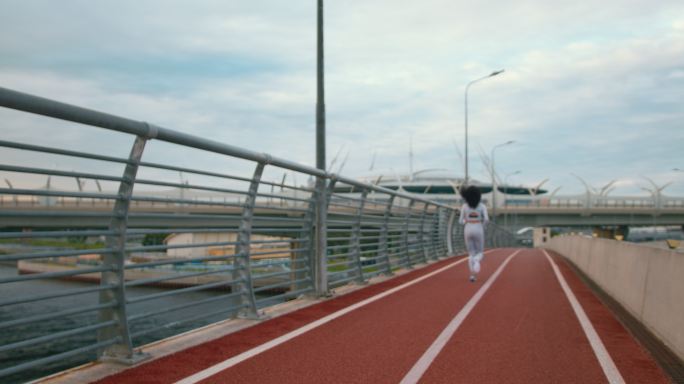 一幅城市景观，桥上有跑道，晚上一位穿着白色慢跑服的苗条女运动员在桥上跑步
