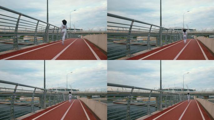 一幅城市景观，桥上有跑道，晚上一位穿着白色慢跑服的苗条女运动员在桥上跑步