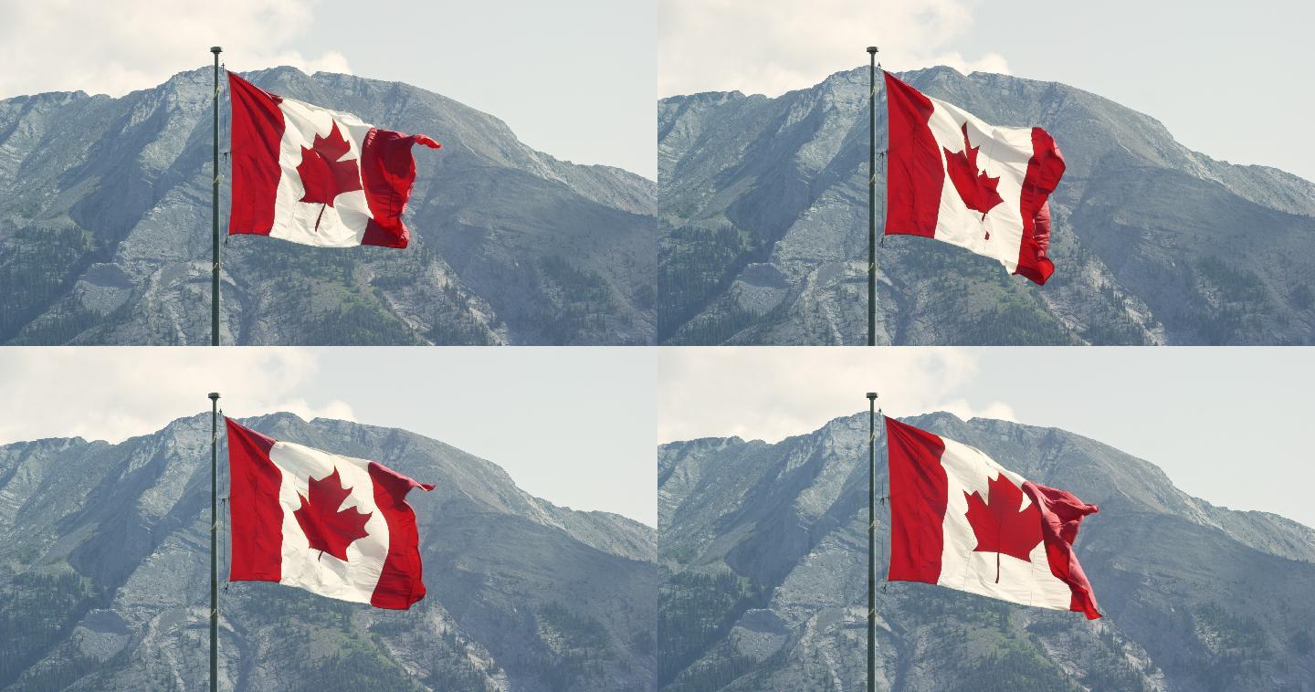 阳光明媚的日子里，加拿大国旗在风中飘扬，背景是一座山的慢镜头