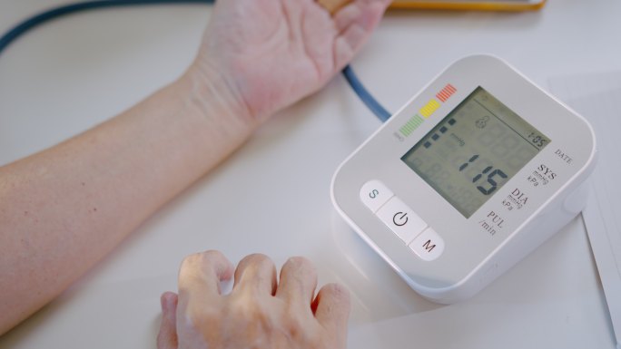 资深女性在家用医疗器械检查血压计和心率。