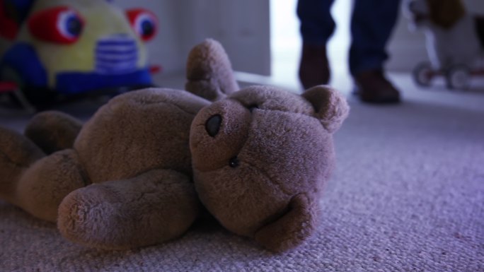 泰迪熊在孩子卧室的地板上一个男人走进房间。推拉镜头。