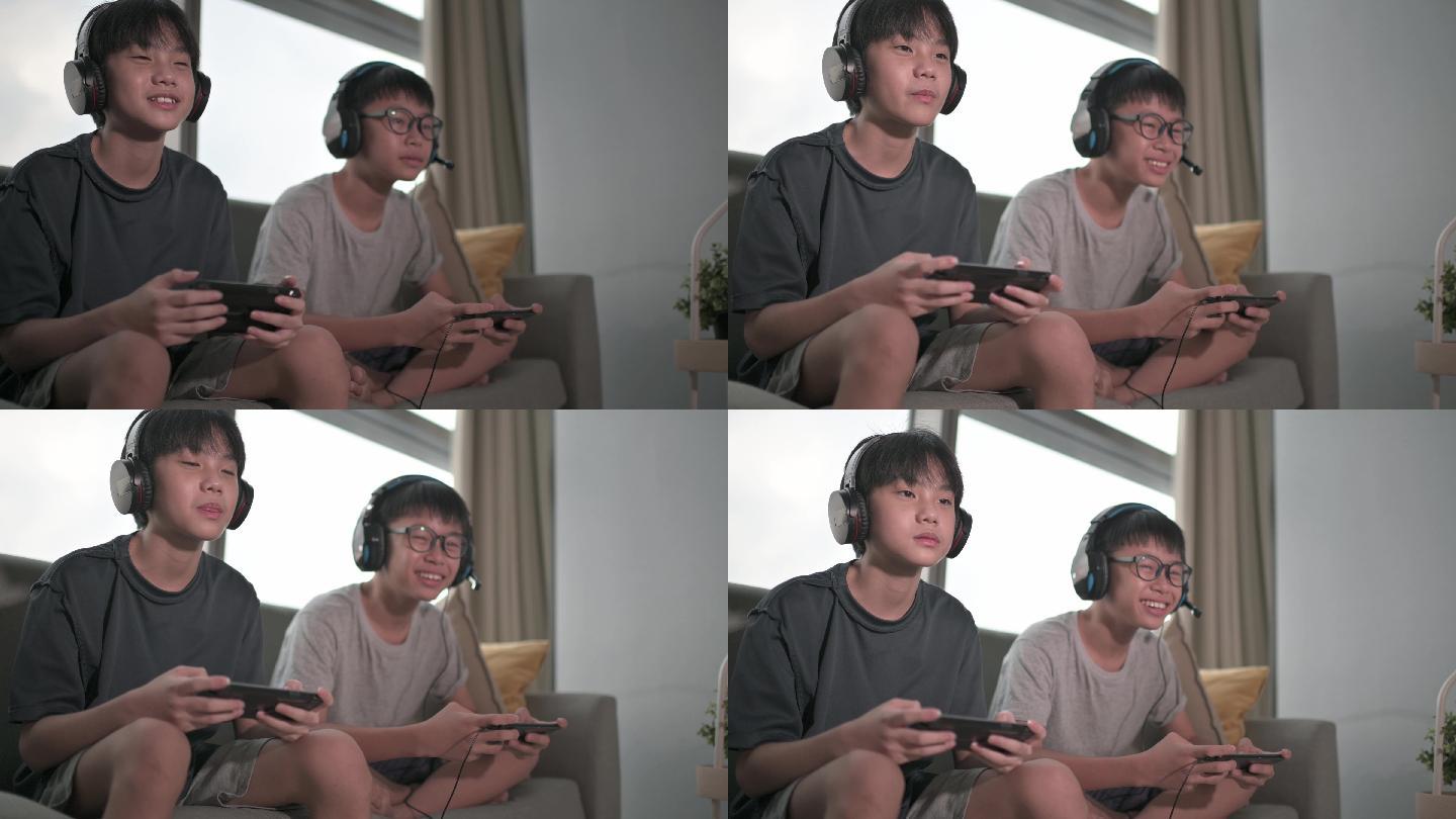 2个亚裔中国少年放学后在客厅玩电子游戏