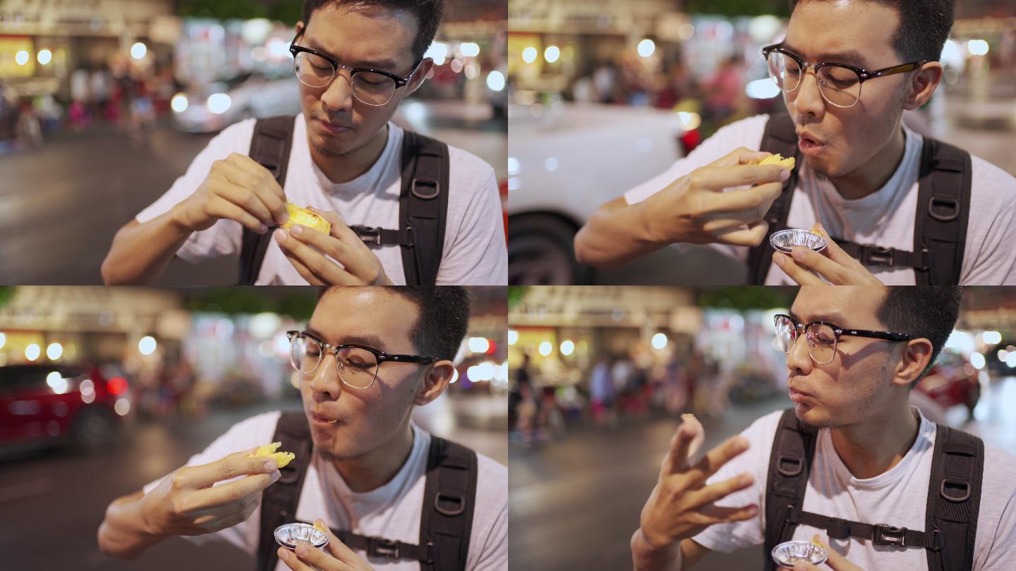 泰国曼谷Yaowarat Street Food Road的亚洲男人吃蛋挞