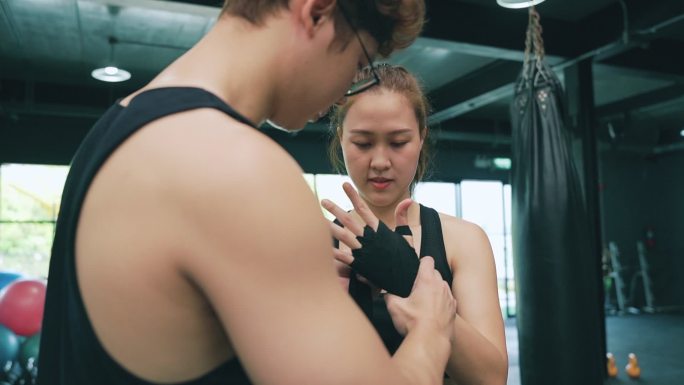 亚洲教练指导教学女运动员在健身房打沙袋