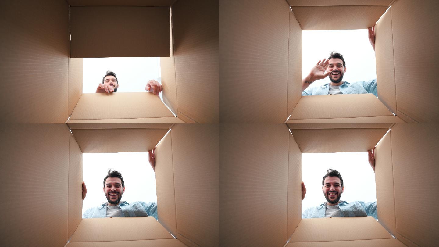 一个快乐的年轻人透过一个纸板箱看的肖像。