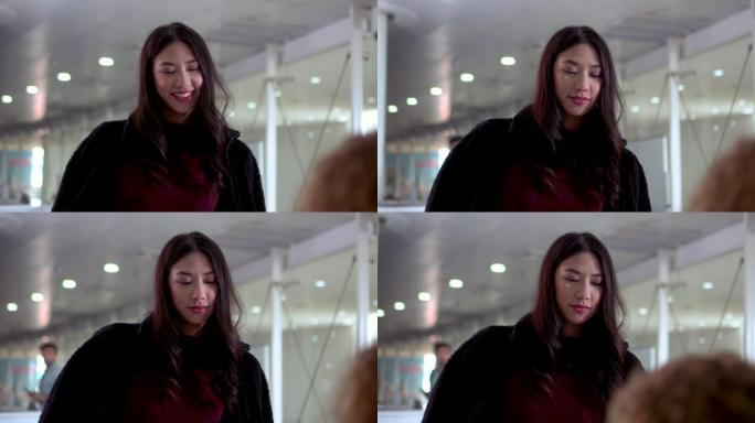 一位微笑的亚洲女性在机场将旅行证件交给值机代理