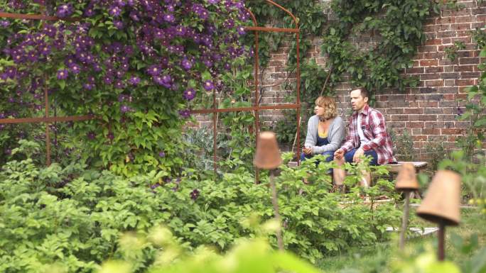 一对夫妇在郁郁葱葱的后院种花休息