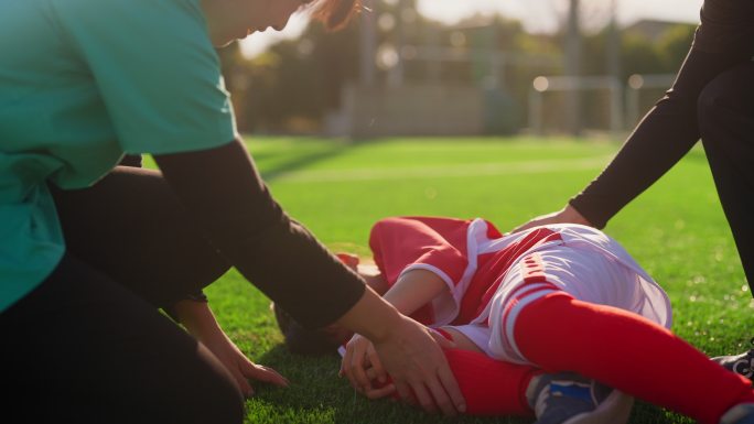 护士检查女性初级足球运动员或足球运动员的受伤情况