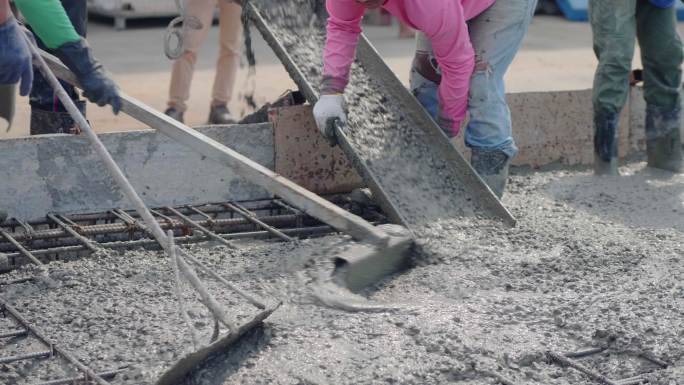 一名亚洲人通过一台倒在地板上的泵送混凝土。