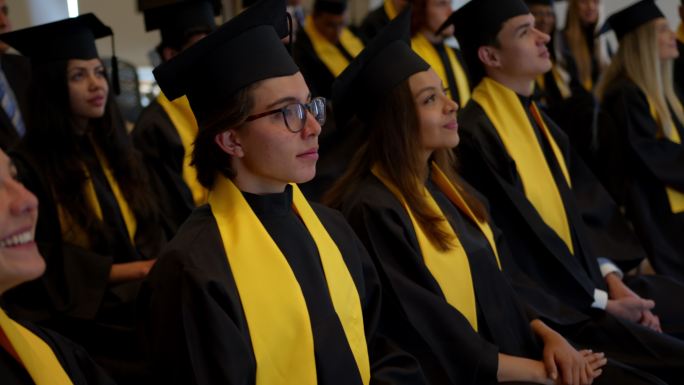 骄傲的年轻男生在毕业典礼上调整了他的毕业帽，看起来都很开心