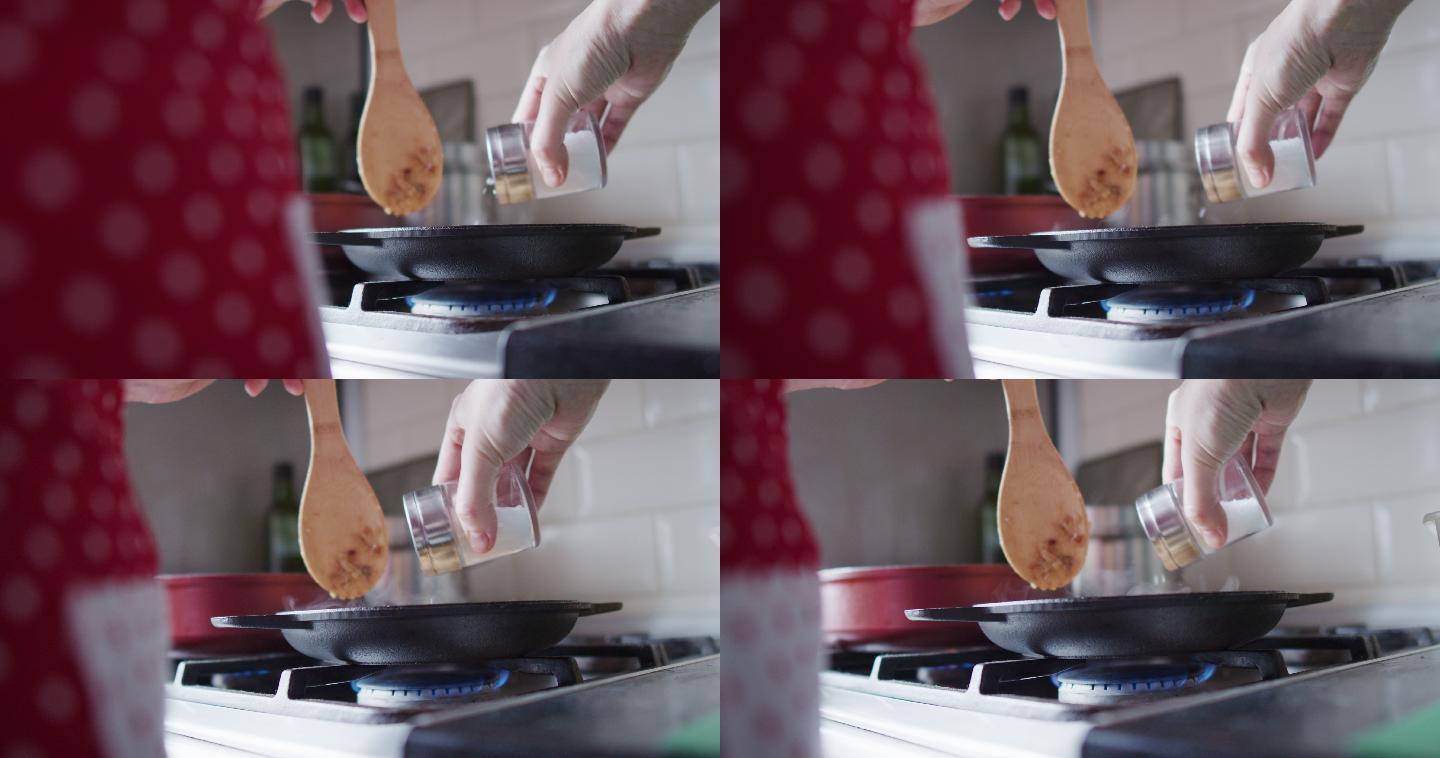 一个面目全非的女人正在家里厨房里煎的食物里加盐
