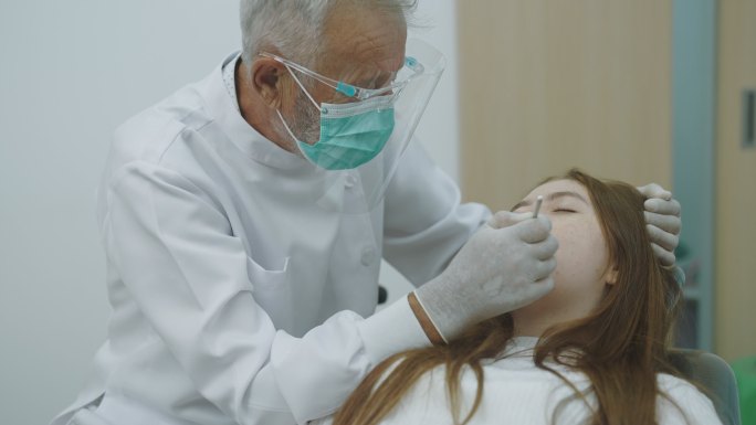 少女在牙医处检查和牙科检查。坐在牙科椅上接受牙科治疗的可爱女孩。医学