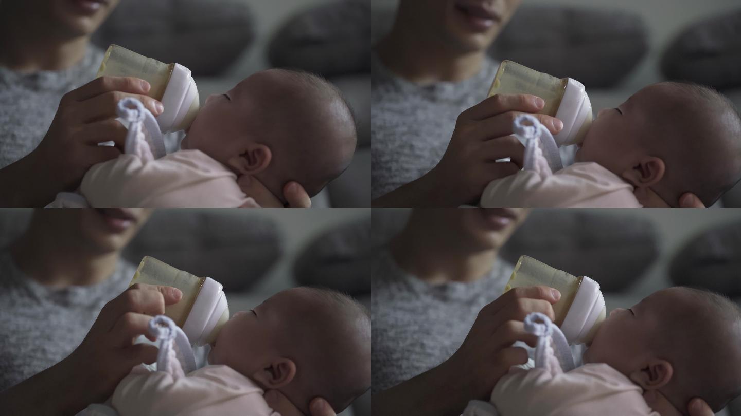 周末，亚裔中国年轻父亲在客厅用奶瓶喂养男婴