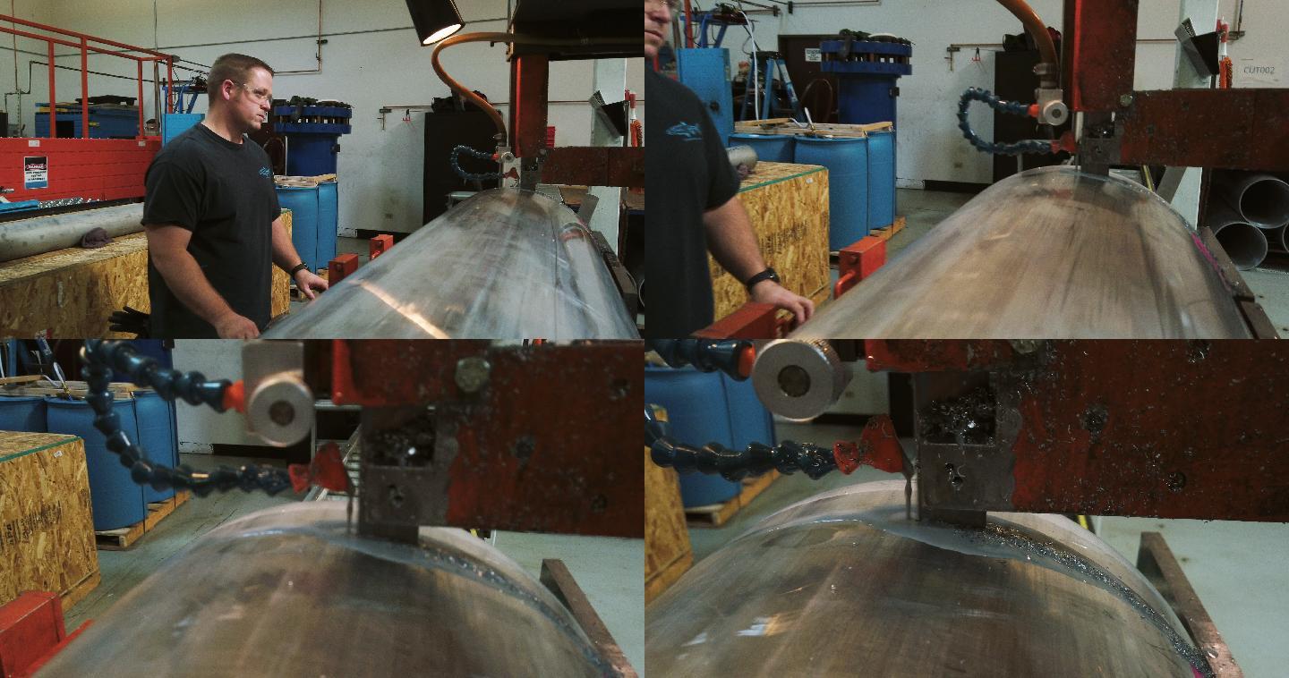 一名30多岁的高加索技术人员在室内制造厂使用大型工业带锯切断旋转成型的钢桶