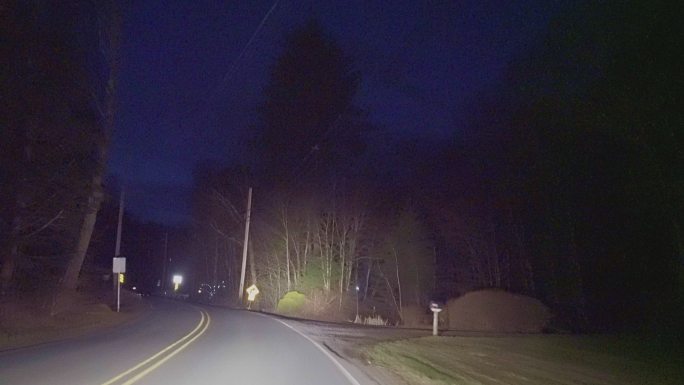 晚上在乡村的公路上开车，穿过山间的森林。
