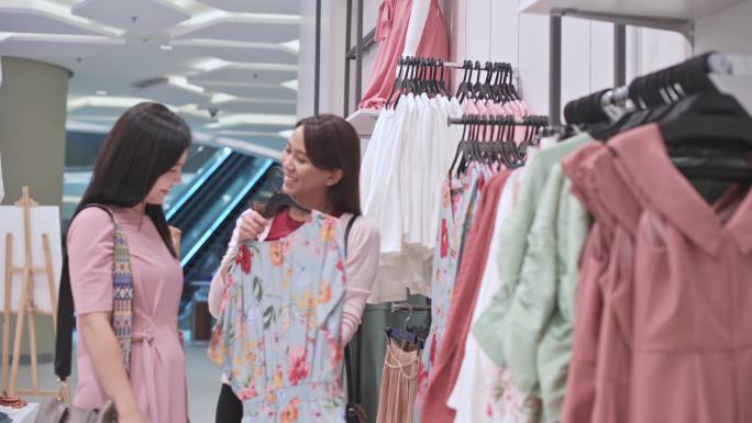 两名中国亚裔女性在服装店戴口罩挑选服装