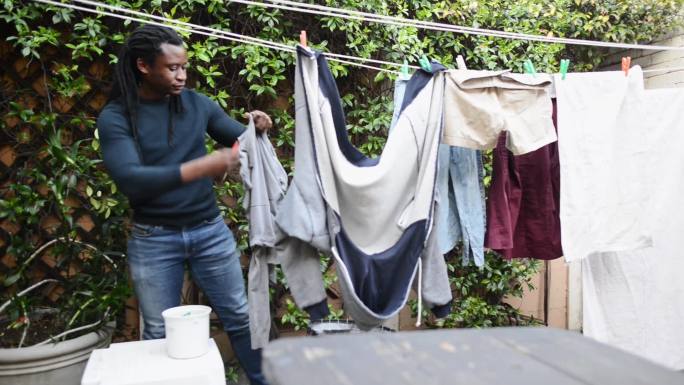 一个年轻人把洗过的衣服挂在院子外面的晾衣绳上